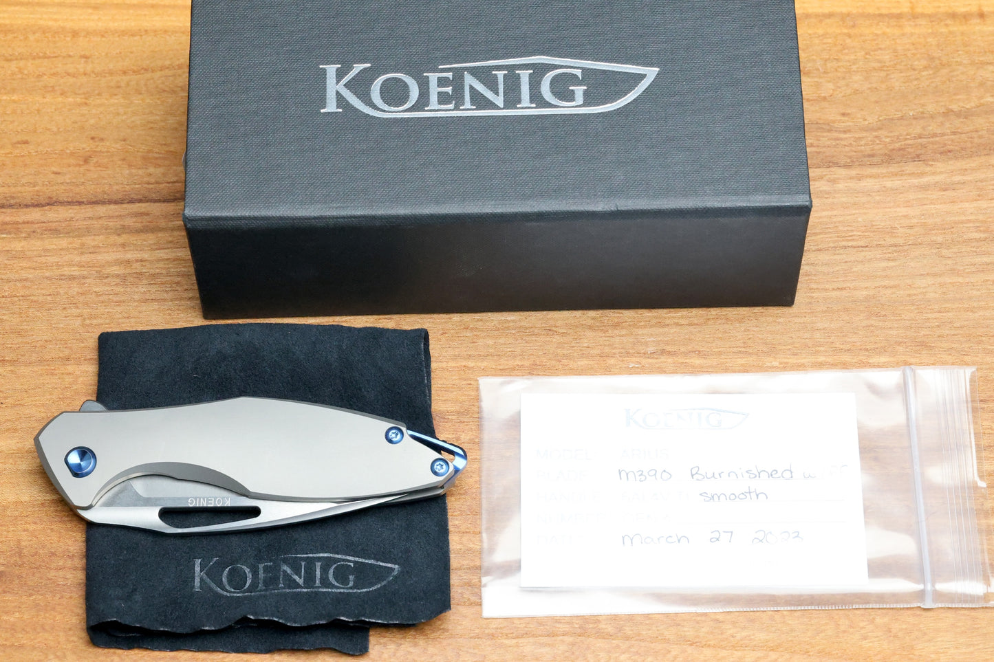 KOENIG KNIVES ARIUS – SMOOTH TITANIUM HANDLE – BLUE HARDWARE – BURNISHED W/ POLISHED FLATS M390 BLADE (PREOWNED)
